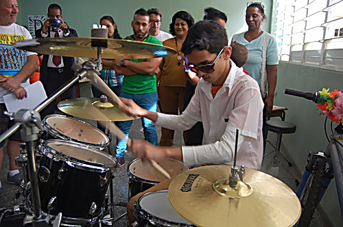 A student tries out a new drum kit donated by sponsored cyclists 